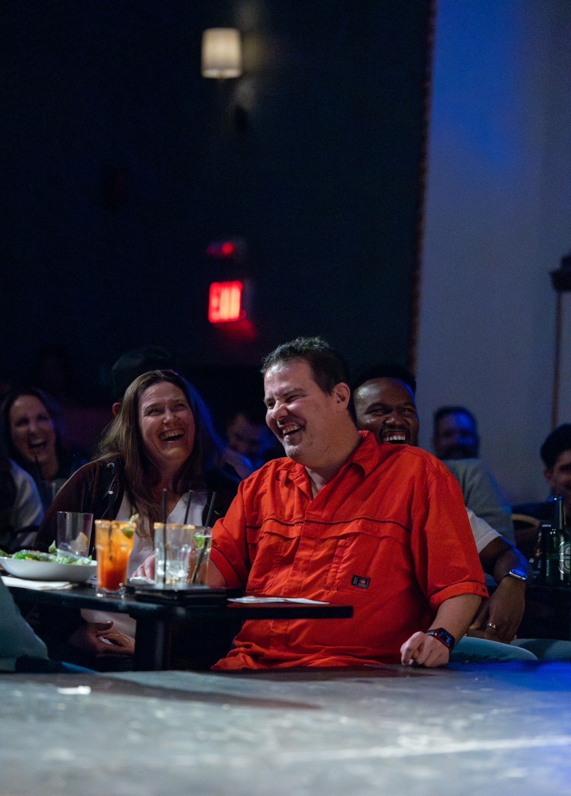 Guests laughing over food and cocktails at a table in House of Comedy Vancouver