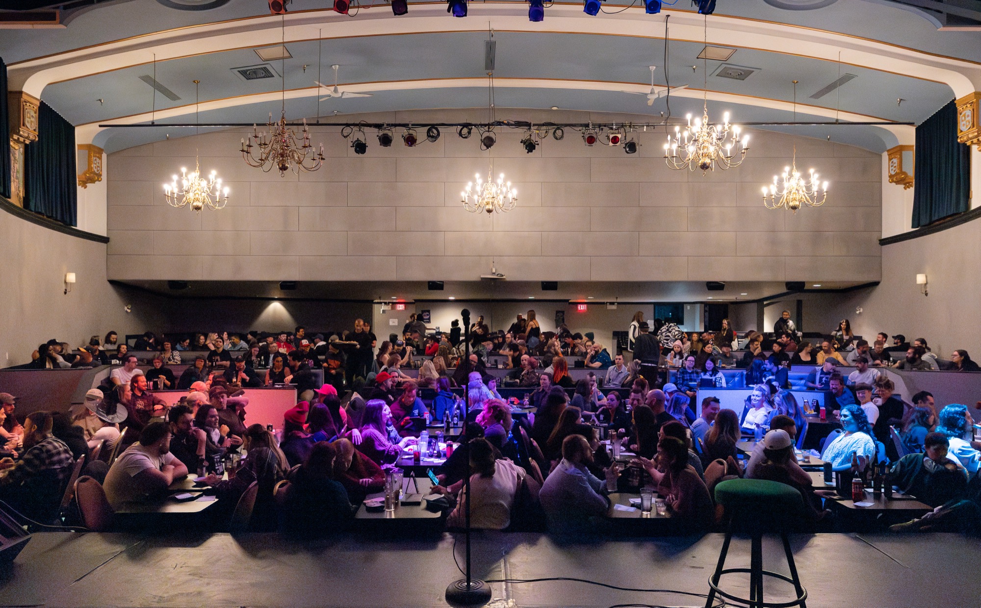 A full room at House of Comedy Vancouver, guests seated at tables beneath the venue's chandeliers